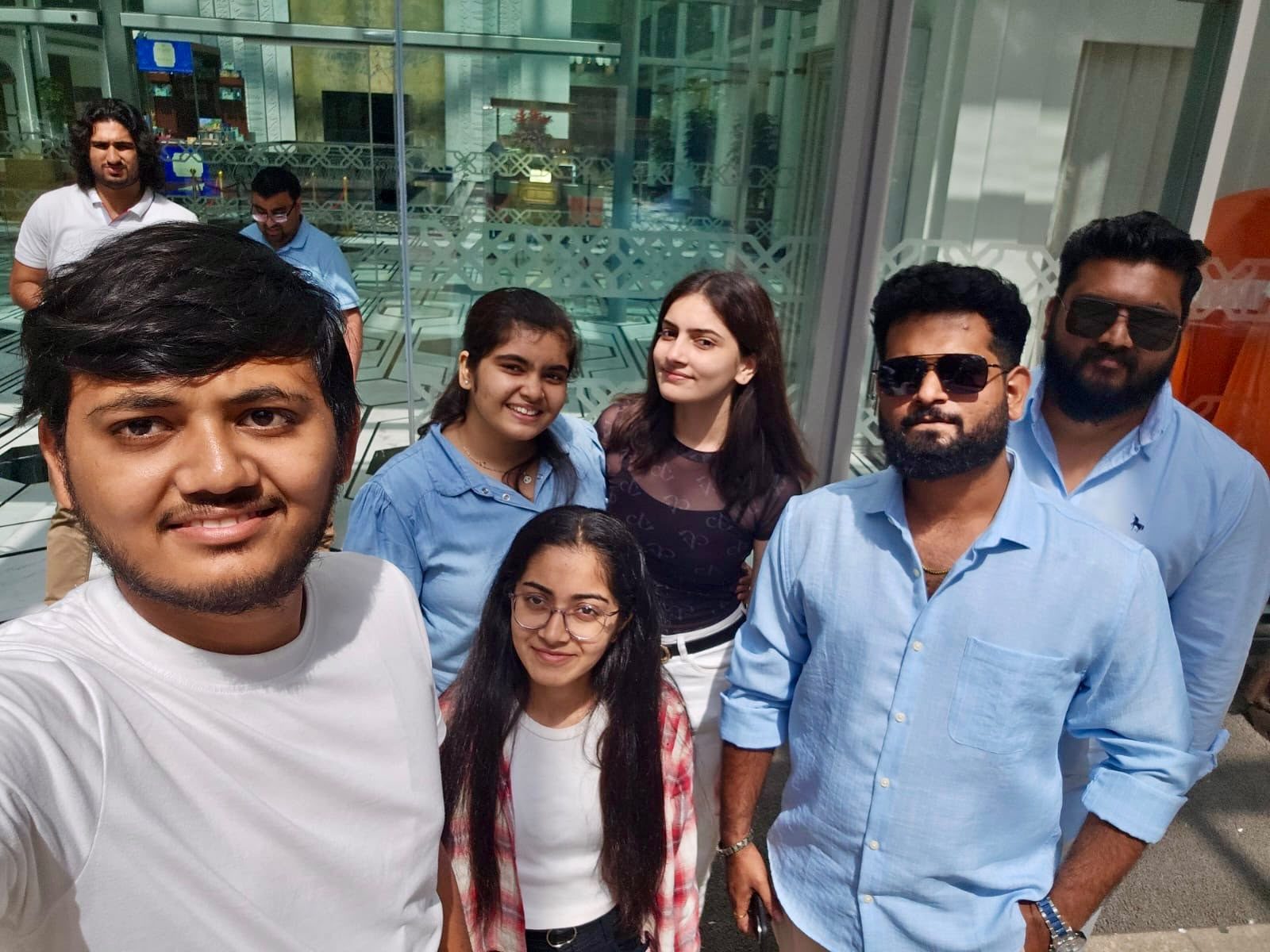 Six KivvaTech team members smiling together for a group selfie outside on a sunny team outing day